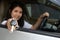 Asian car driver woman smiling showing new car key..Happy young girl owner taking car key from dealer in auto showÂ room.